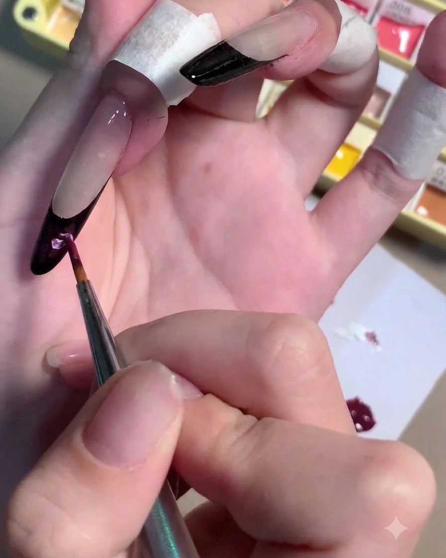 Un pinceau incorporant du gel blanc dans une flaque de pigment prune foncé sur une palette.