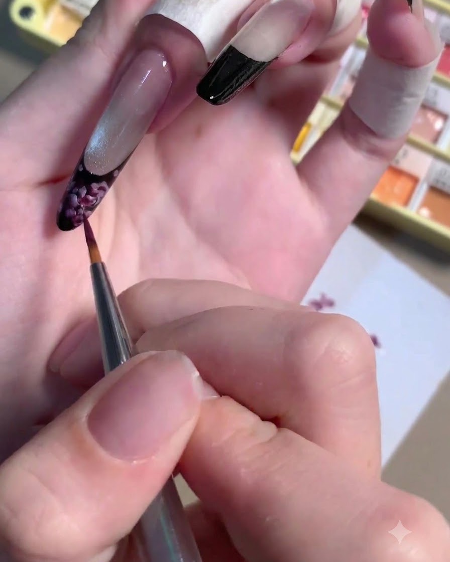 Un pinceau liner effilé appliquant une micro-goutte de gel prune foncé au cœur dune rose peinte.