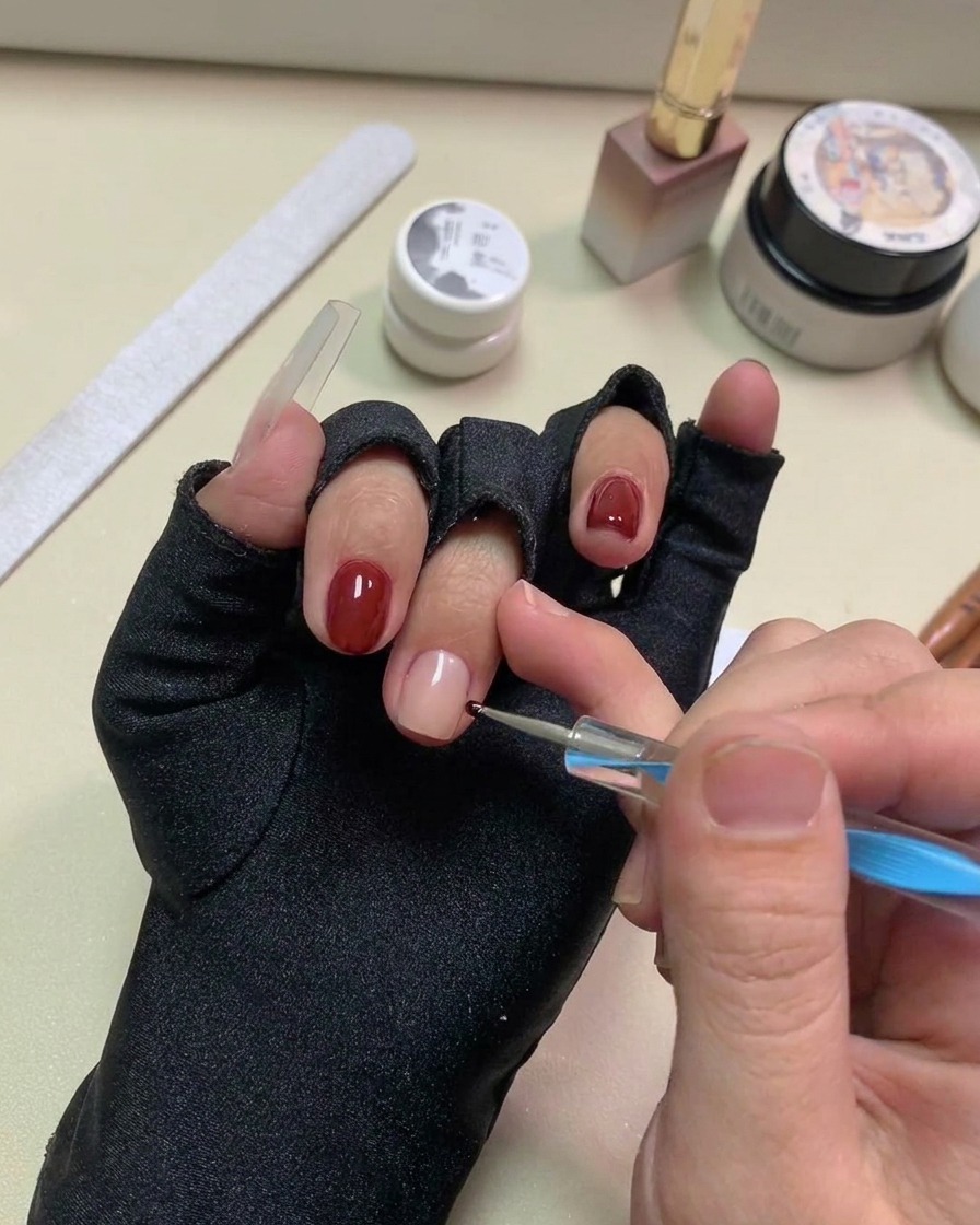 Un stylo à dotting plaquant de petits points de gel noir sur la surface de longle nude.