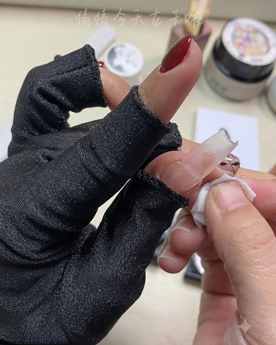 Gros plan dune main nettoyant un doigt avec un coton imbibé près dun nail art préparé.