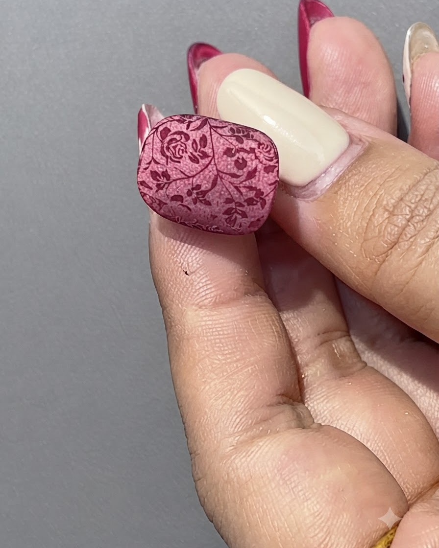 Une main tenant un flacon de gel cat eye rouge à côté dun support de présentation transparent pour ongles.