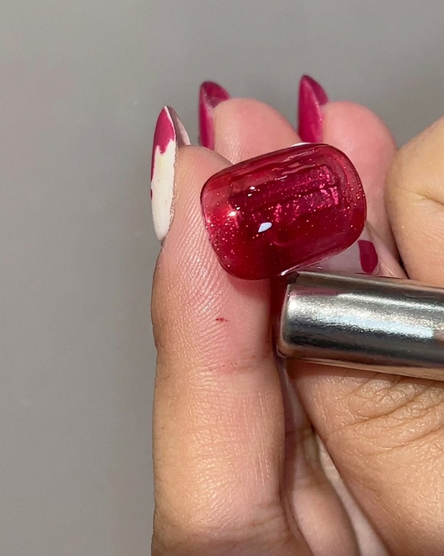 Vue rapprochée dun ongle en gel cat eye rouge catalysé montrant une base cramoisie profonde avec une ligne de lumière magnétique concentrée.
