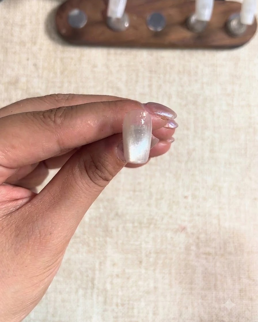 Un ongle de majeur catalysé sous une lampe, montrant un fini cat-eye figé.