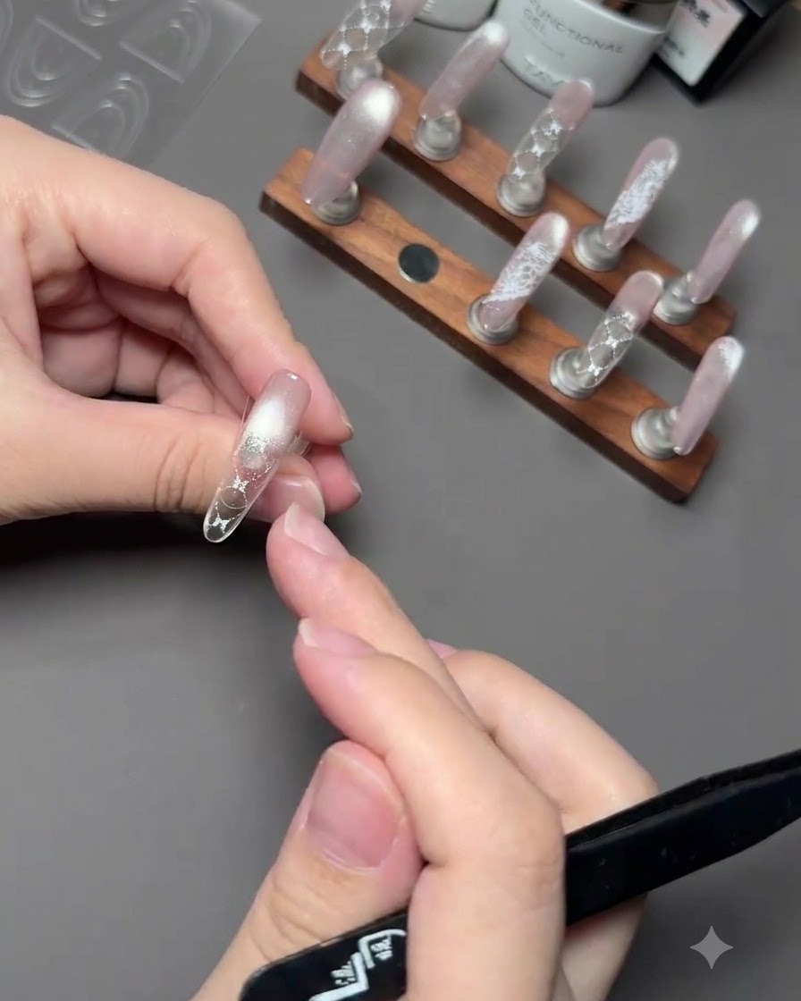 Une main tenant un pinceau pour appliquer du gel polish rose sur le bout dun ongle au-dessus dun autocollant guide.