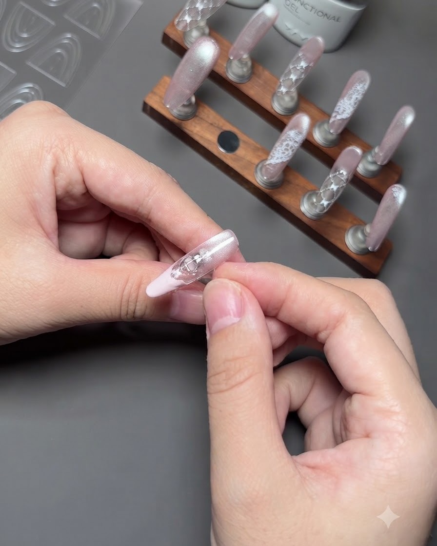 Gros plan de doigts retirant délicatement un autocollant guide dun ongle pour révéler une french rose soignée.