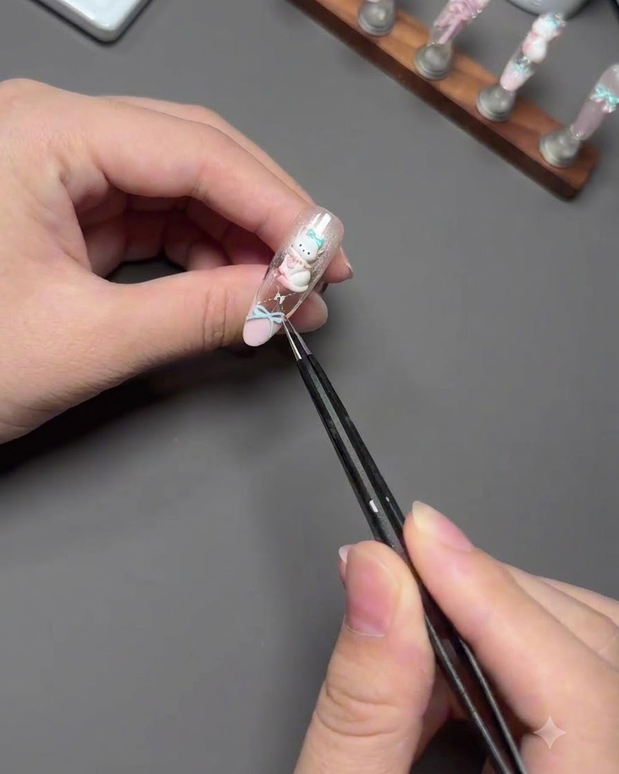 Des brucelles plaquant avec précaution un charm de chat 3D sur un ongle décoré.