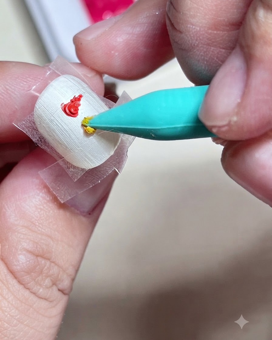 Un outil en silicone appliquant une goutte de gel paint jaune juste en dessous du rouge dans le carré délimité sur longle.