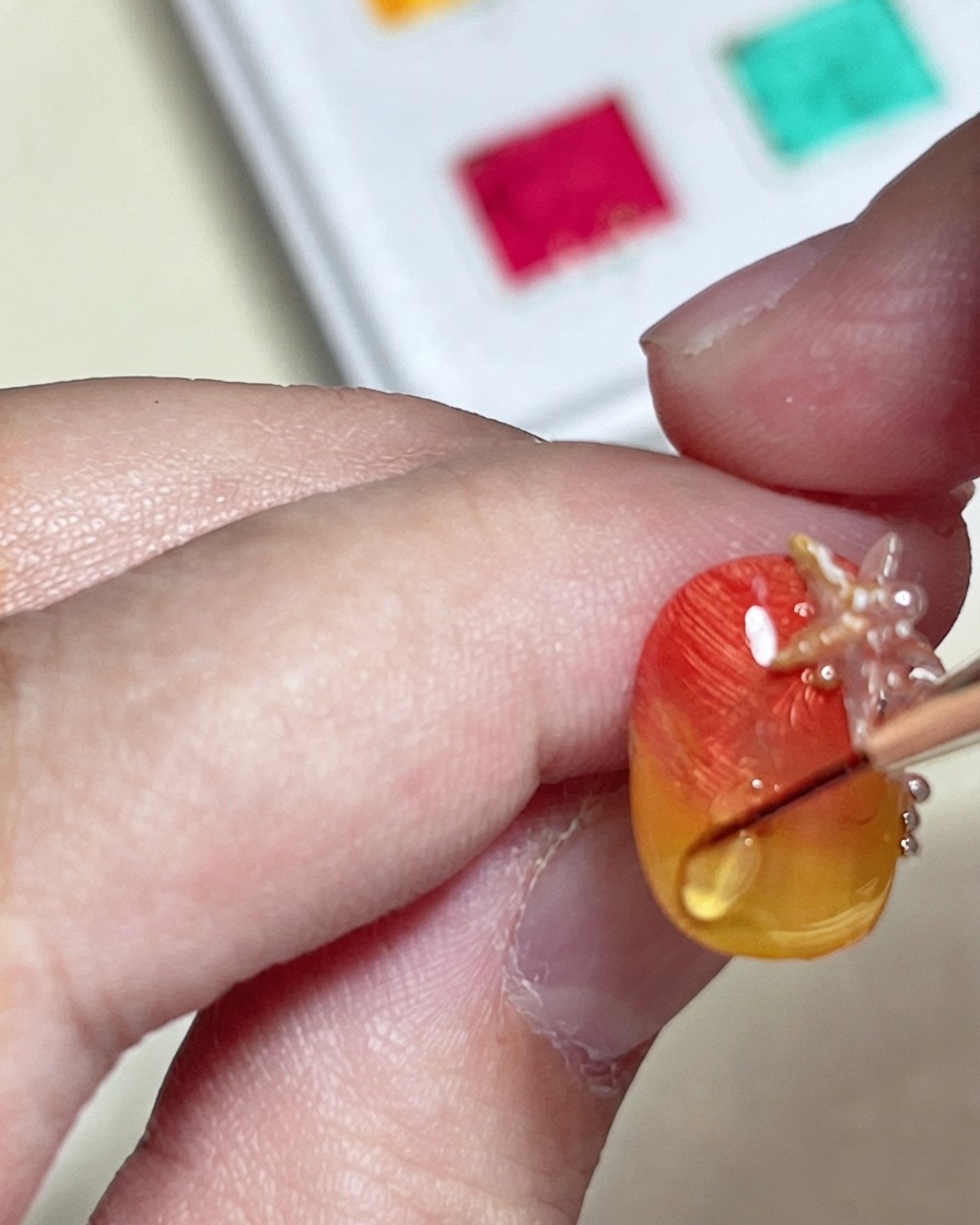 Un pinceau dessinant une ligne dondulation deau en relief avec un top coat dur sur longle dégradé.