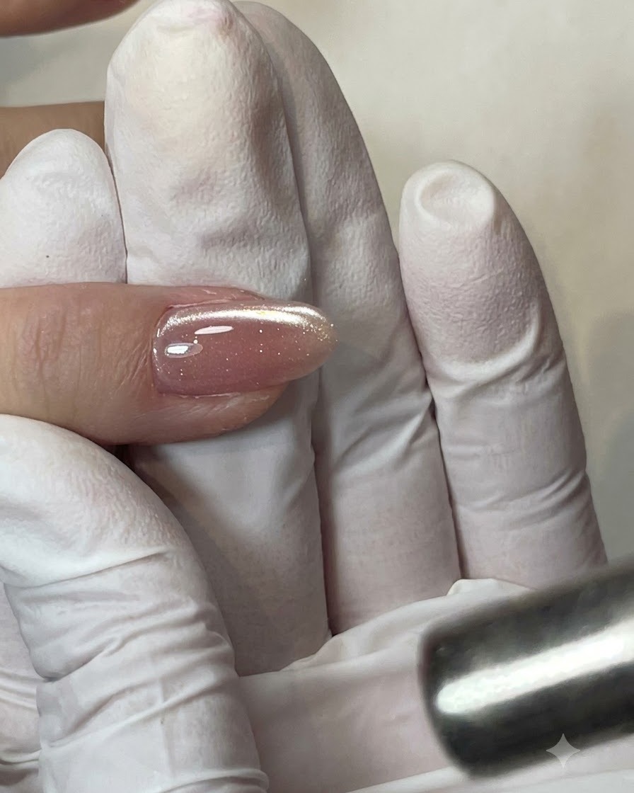 Un pinceau plat appliquant une couche transparente de base gel sur la plaque de longle.