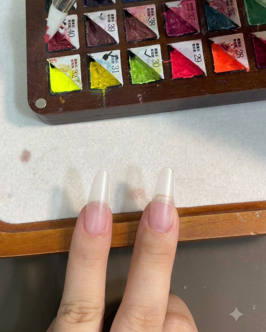 Un pinceau en silicone prélevant du gel couleur rose sur une palette compartimentée.