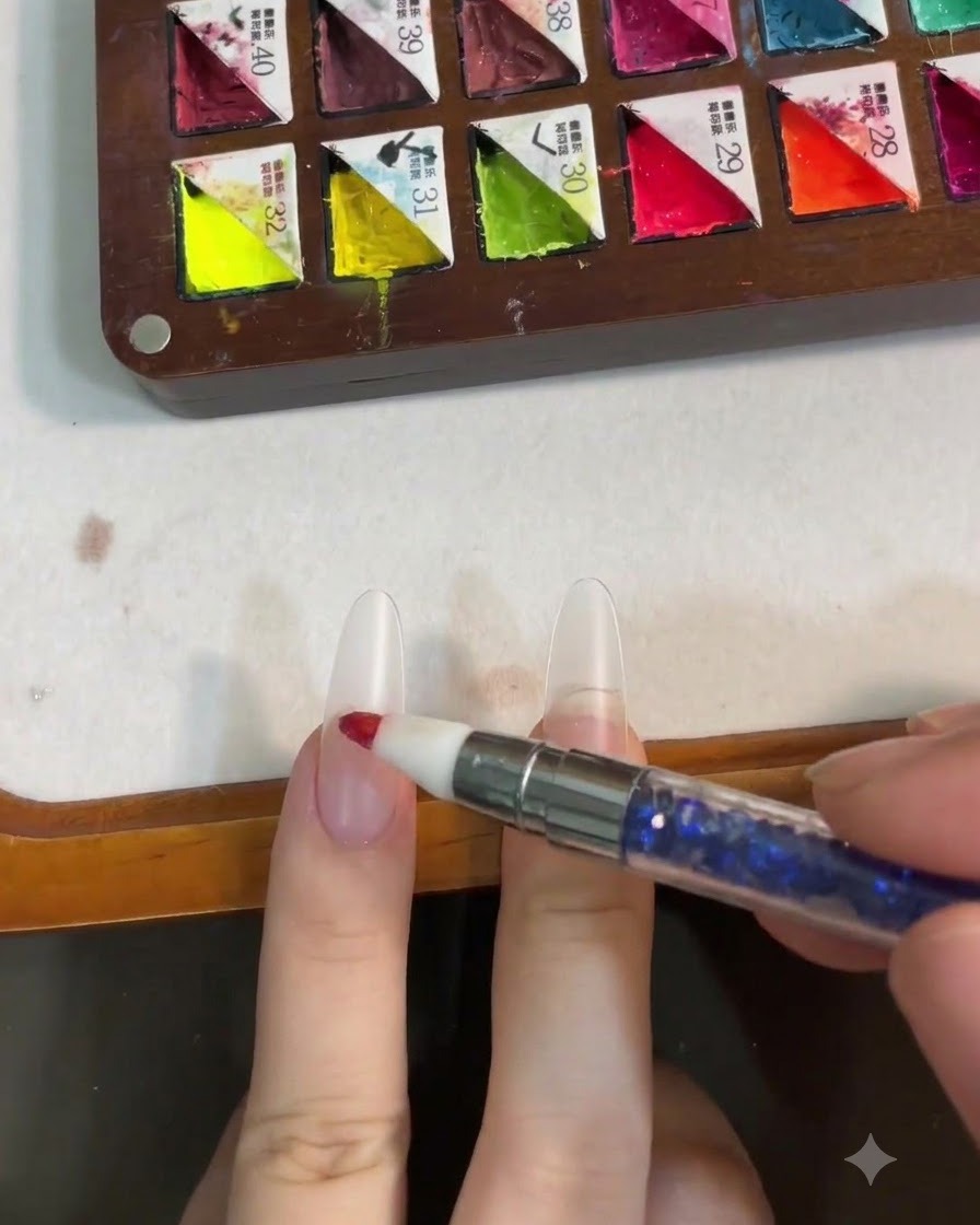 Un outil en silicone déposant du gel rose au centre de longle pour former un effet blush.