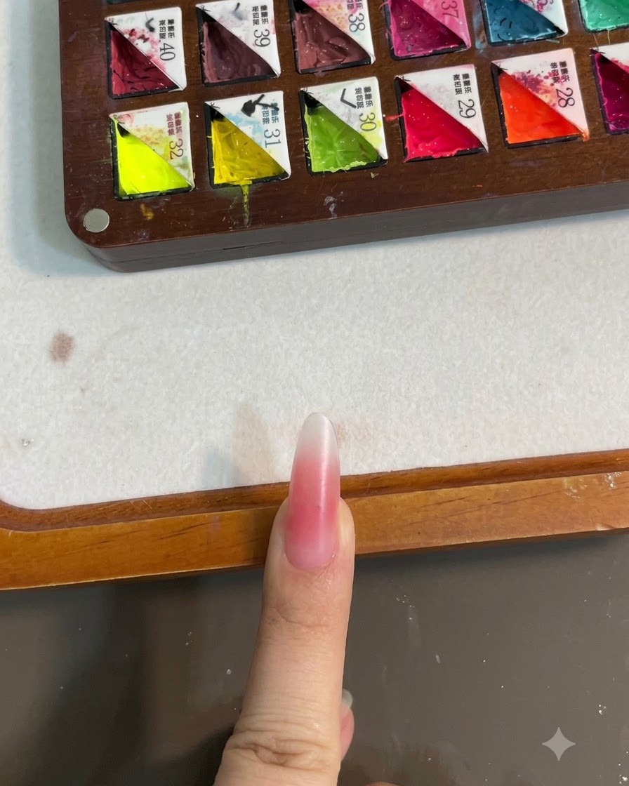 Un ongle orné dun dégradé rose blush sous une lampe UV pour catalyse.
