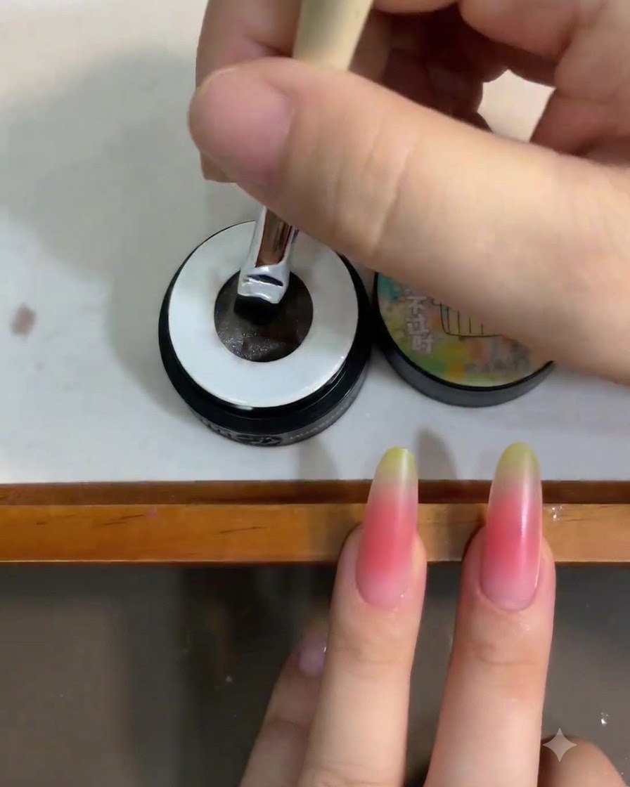 Un pinceau à ongle trempé dans un petit pot de gel cat eye blanc translucide.