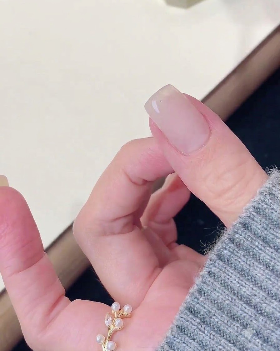 Un doigt reposant après avoir été catalysé sous une lampe à ongles, avec une lingette nettoyant la surface.
