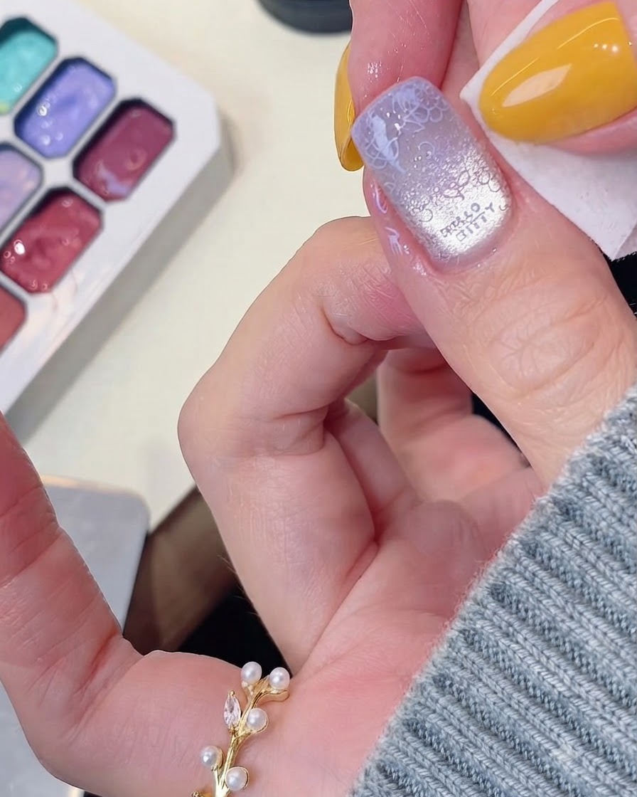 Une lingette nettoyant lexcès de gel sur les bords dun ongle manucuré.