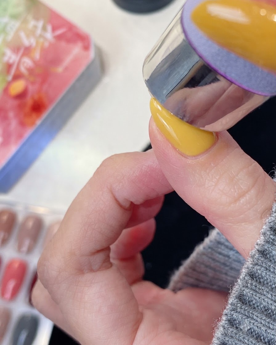 Un doigt manucuré positionné sous une lampe à ongles UV ou LED pour la catalysation.