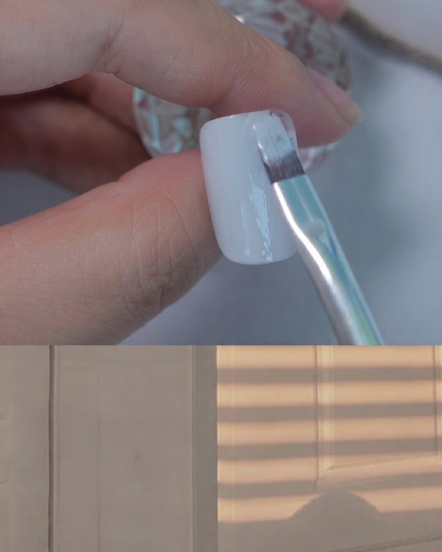 Un pinceau à gel plat appliquant une couche lisse de vernis gel gris clair sur un ongle de présentation.