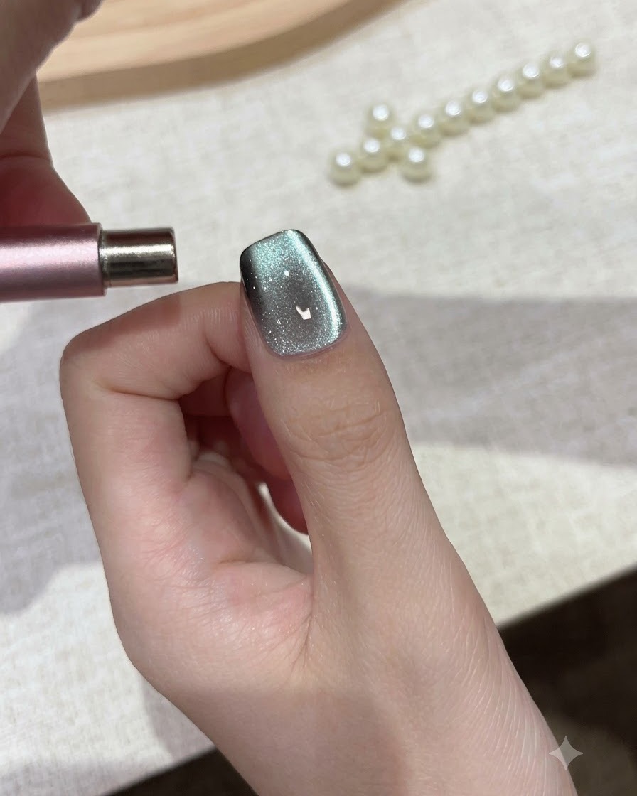 Un aimant cylindrique tenu parallèlement à la pointe de longle pour façonner les particules de gel cat eye.