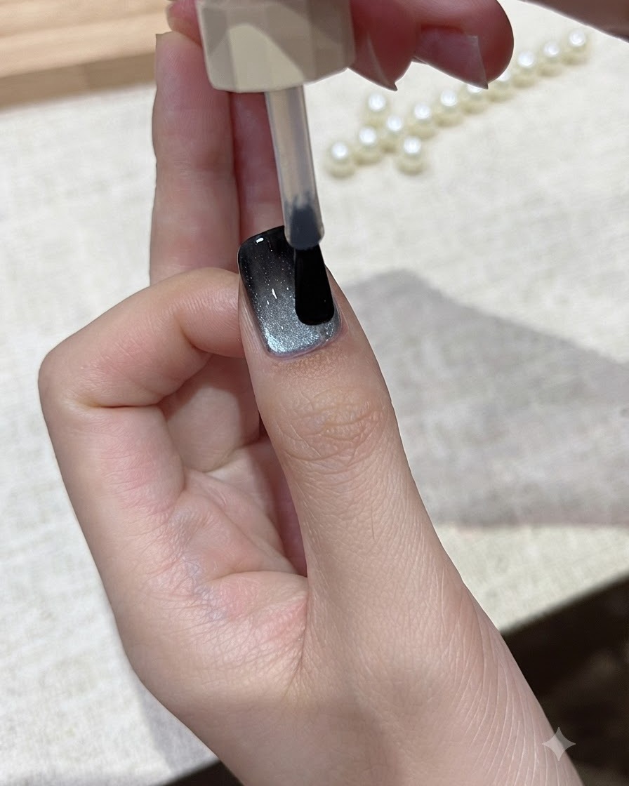 Un pinceau glissant une couche de top coat transparent et brillant sur le design dongle cat-eye terminé.