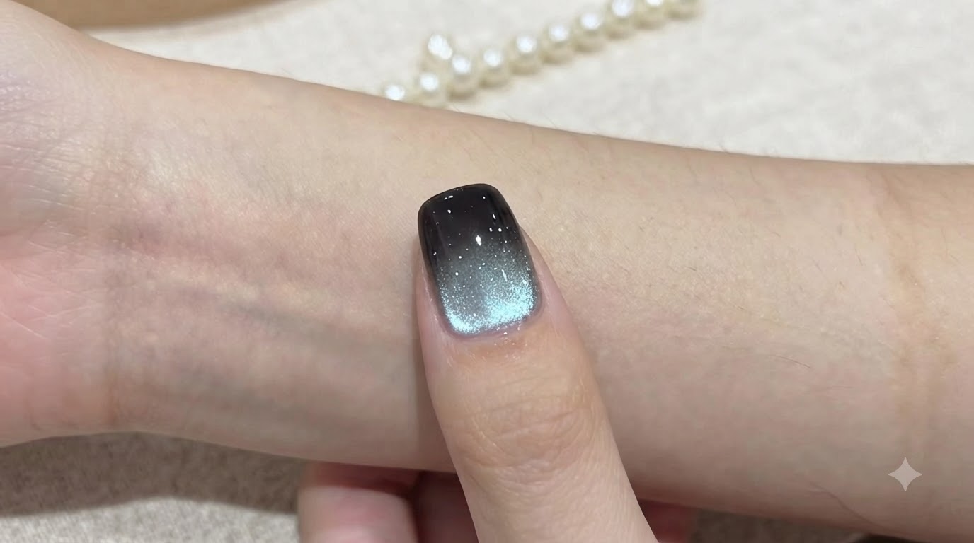 Un ongle cat eye ombré aigue-marine terminé avec une pointe noire profonde et un reflet magnétique bleu-argenté chatoyant.