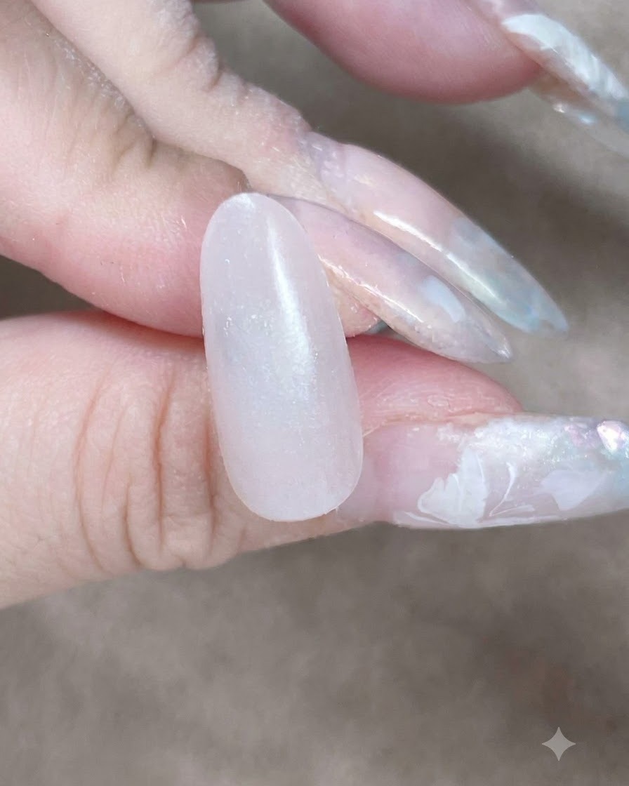 Un gros plan dune éponge à maquillage tapotant le long de la cuticule et du bord latéral pour estomper une couche de base en gel.
