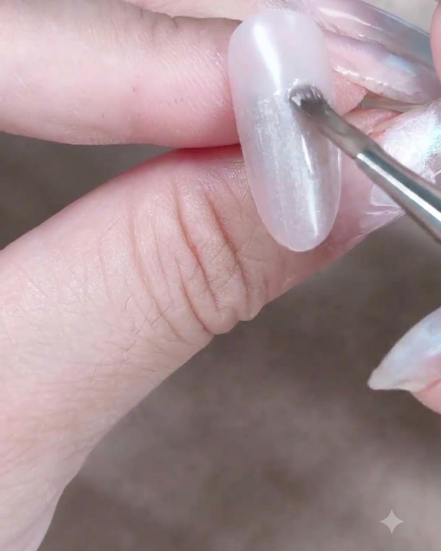 Un aimant cylindrique tenu près dun ongle en gel cat-eye humide pour attirer et déplacer les particules de nacre magnétique.