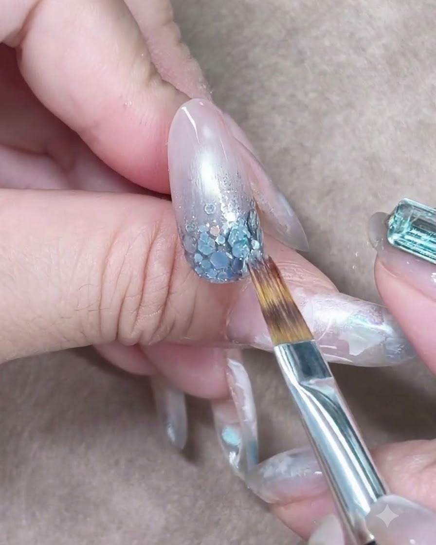 Un pinceau caressant légèrement le gel bleu translucide vers le bas pour estomper le dégradé de couleur.