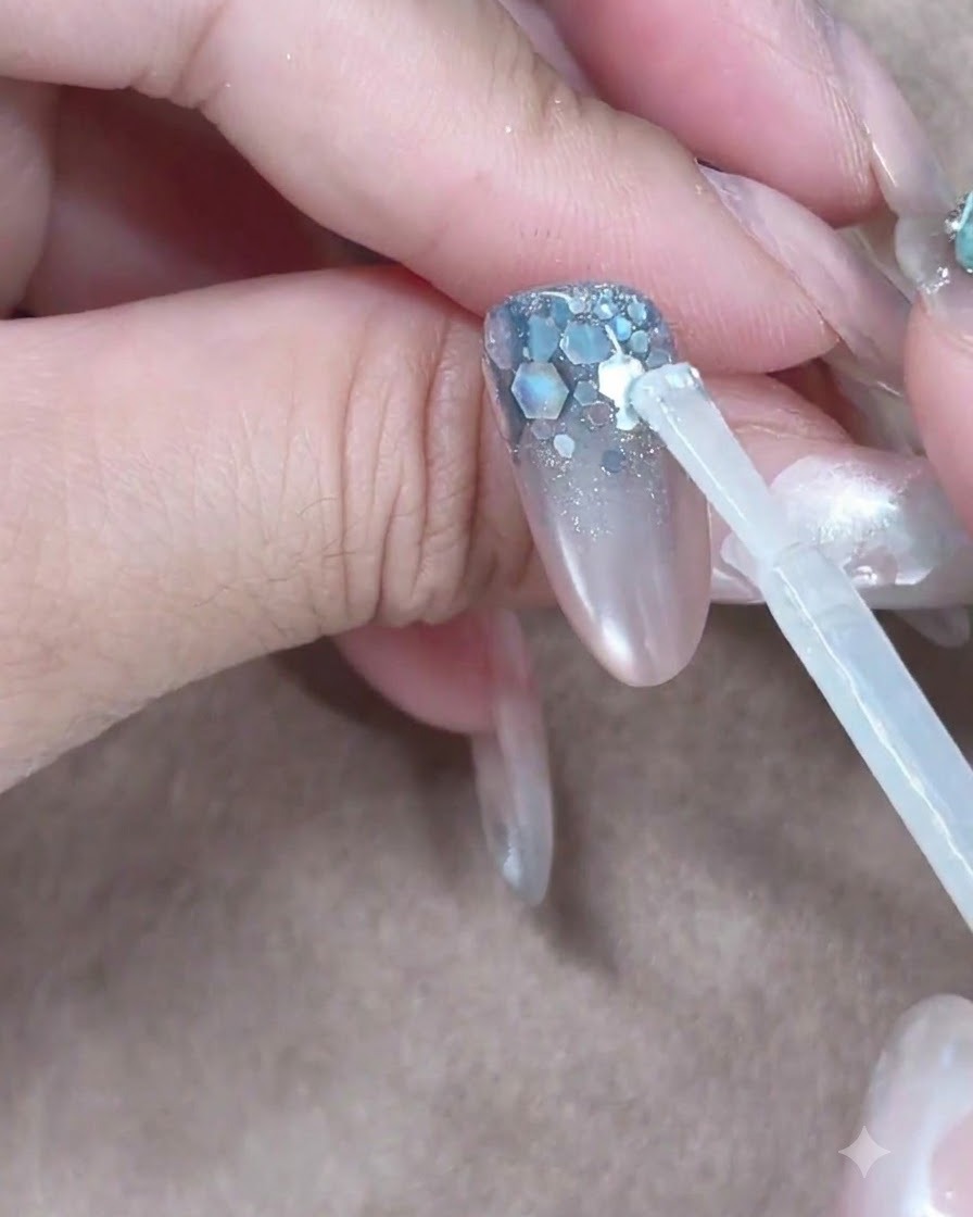 Un pinceau de gel de construction plaquant une boule transparente près des cuticules pour la faire glisser le long de longle.
