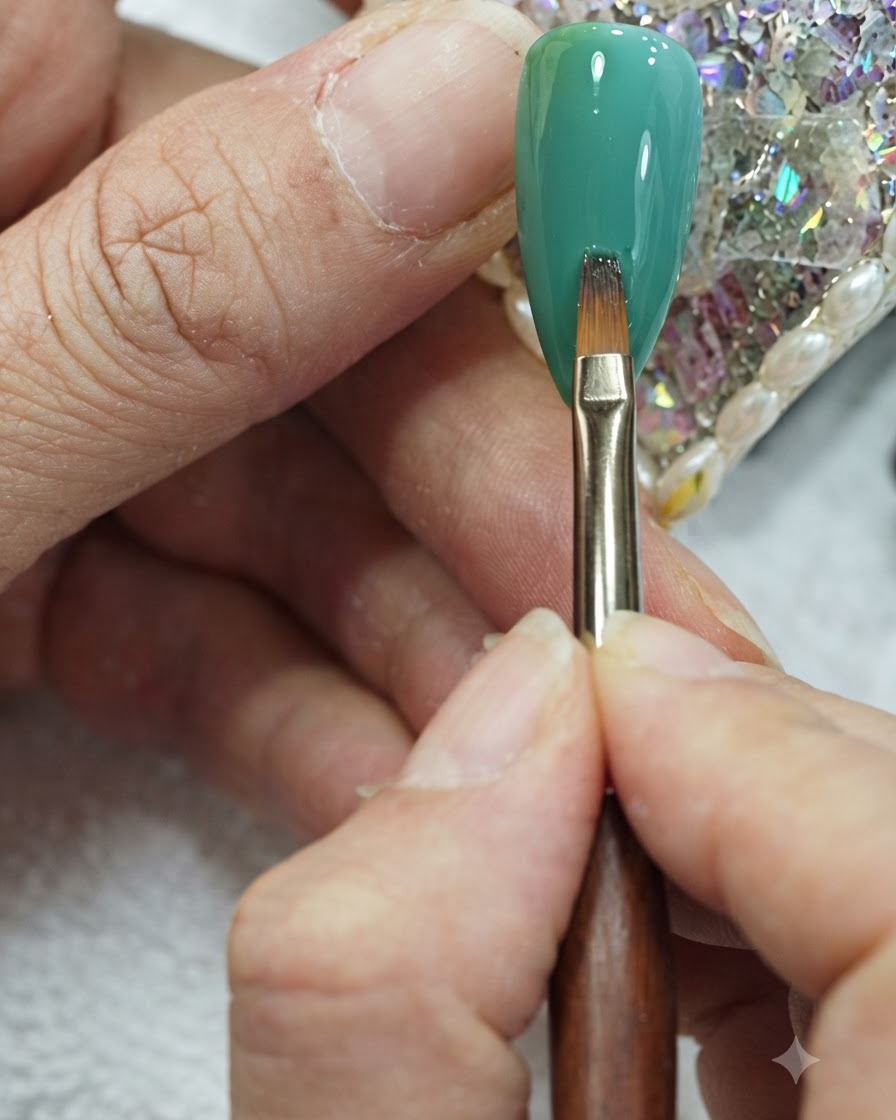 Un pinceau plat pour nail art effectuant de doux mouvements verticaux au centre dun ongle en dégradé vert et teal.