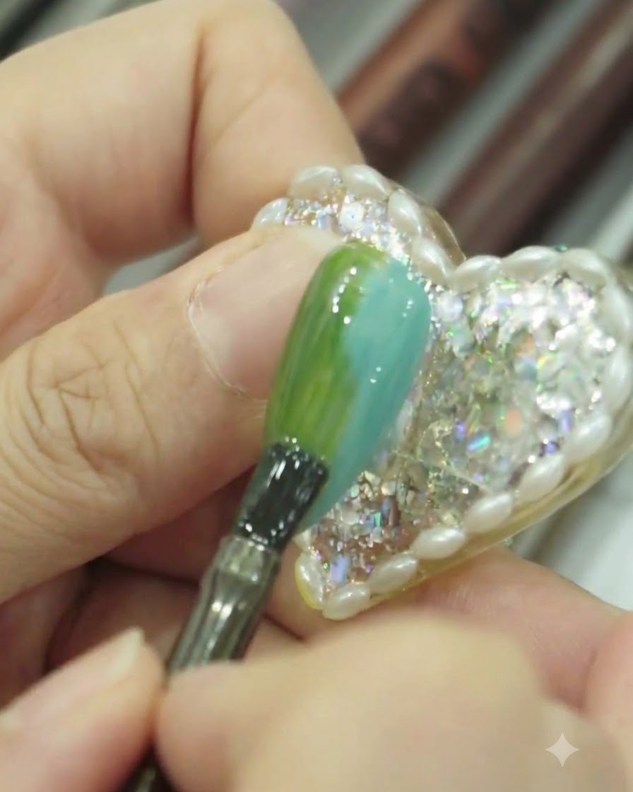 Vue en gros plan dun pinceau tapotant et lissant légèrement la surface dun ongle en dégradé bleu et vert.