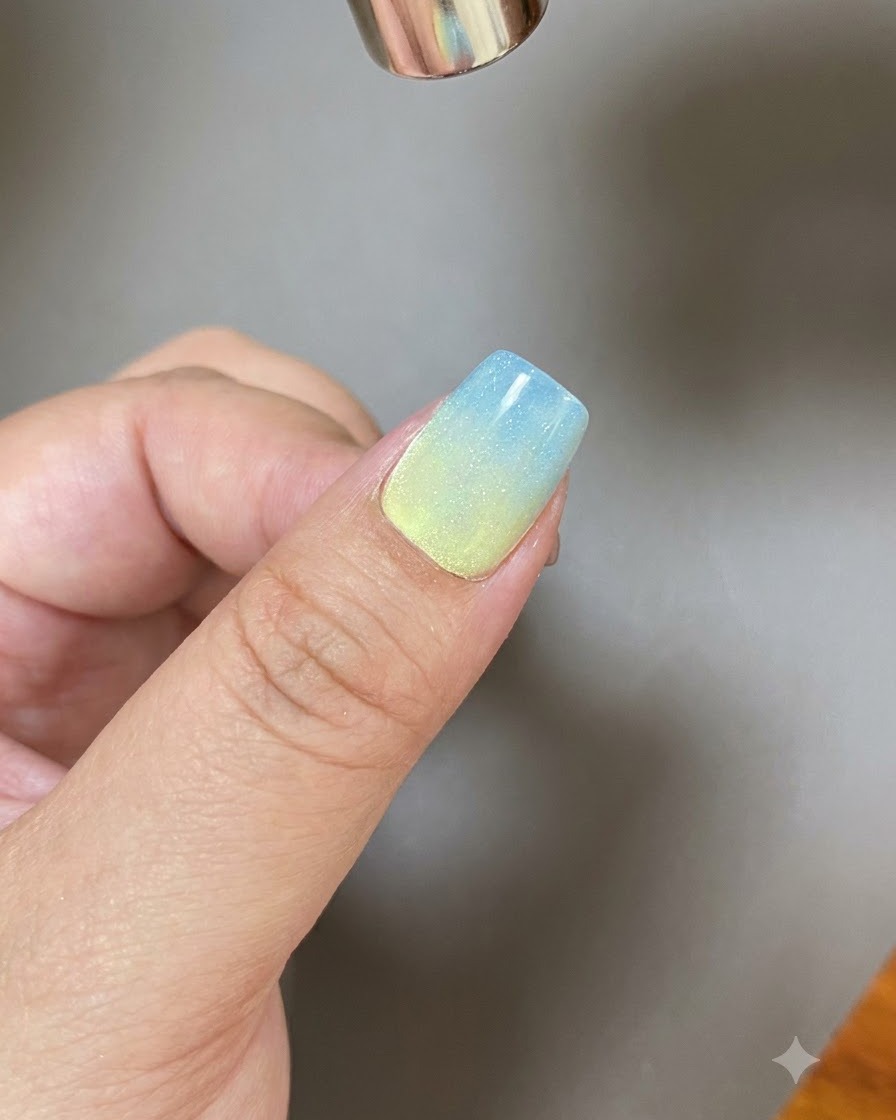 Un outil magnétique façonnant une large traînée de lumière à travers un ongle recouvert de gel scintillant.