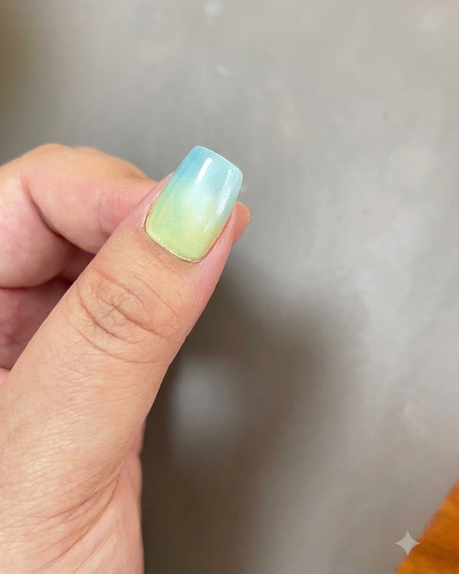 Un ongle avec une base ombrée bleu-jaune et un effet lumineux magnétique cat eye circulaire positionné sous une lampe de catalyse UV/LED violette.