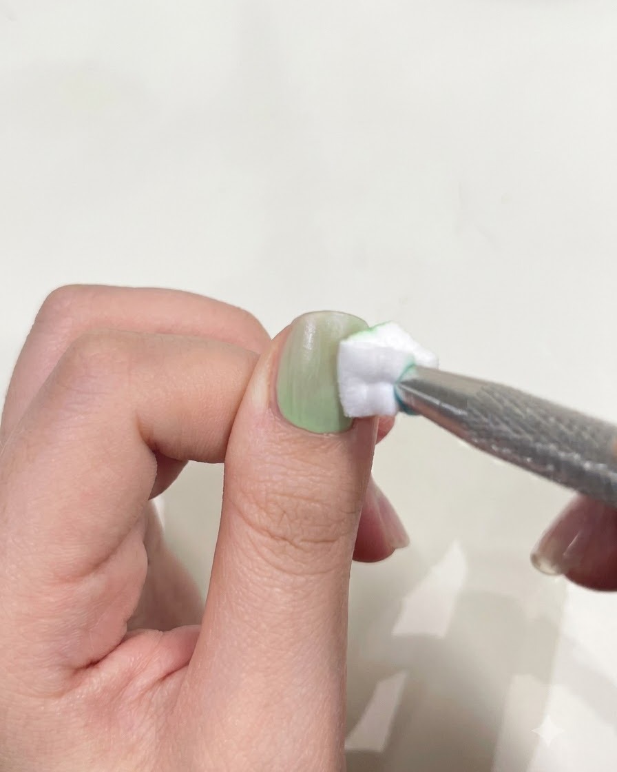 Un pouce positionné sous une mini lampe torche UV/LED compacte pour catalyser le vernis gel.