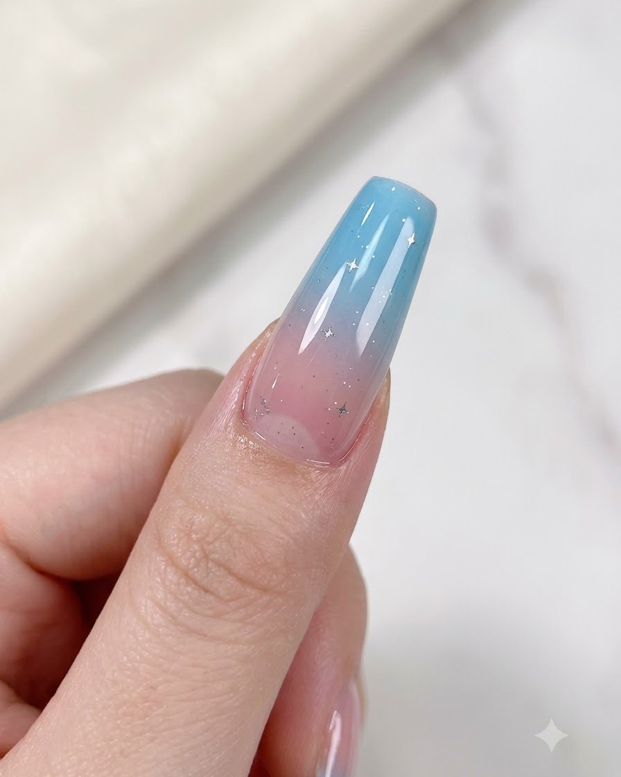 Un doigt avec un ongle dégradé orné de délicates étoiles argentées placé sous une lampe UV/LED.