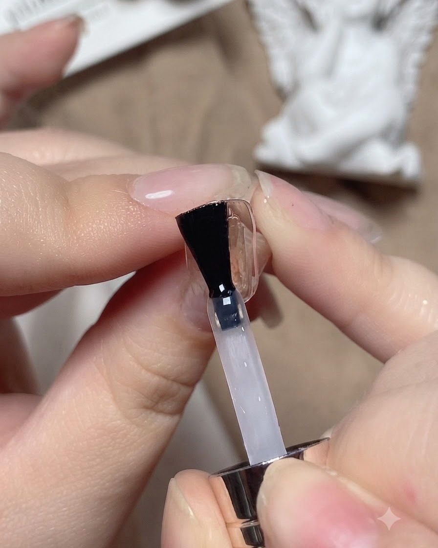 Un pinceau appliquant une base transparente sur un ongle dentraînement.