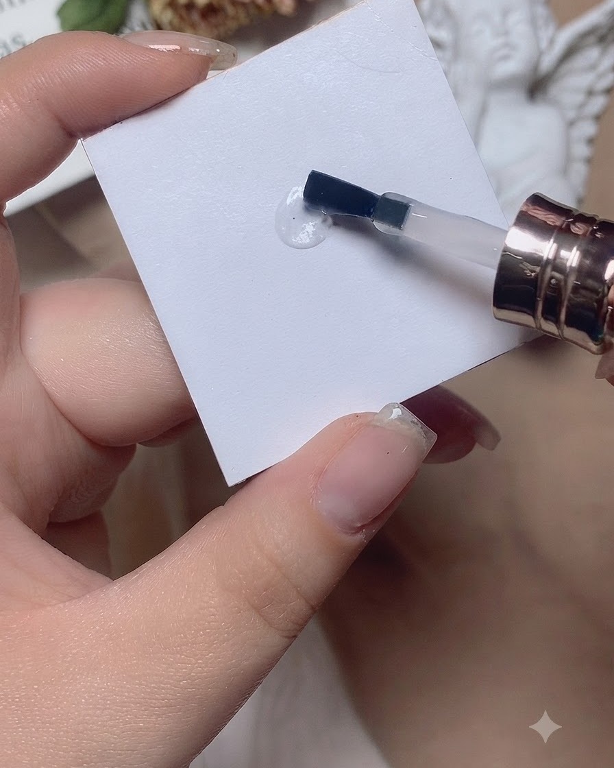Un pinceau travaillant une goutte de base par des mouvements de va-et-vient sur une palette blanche.
