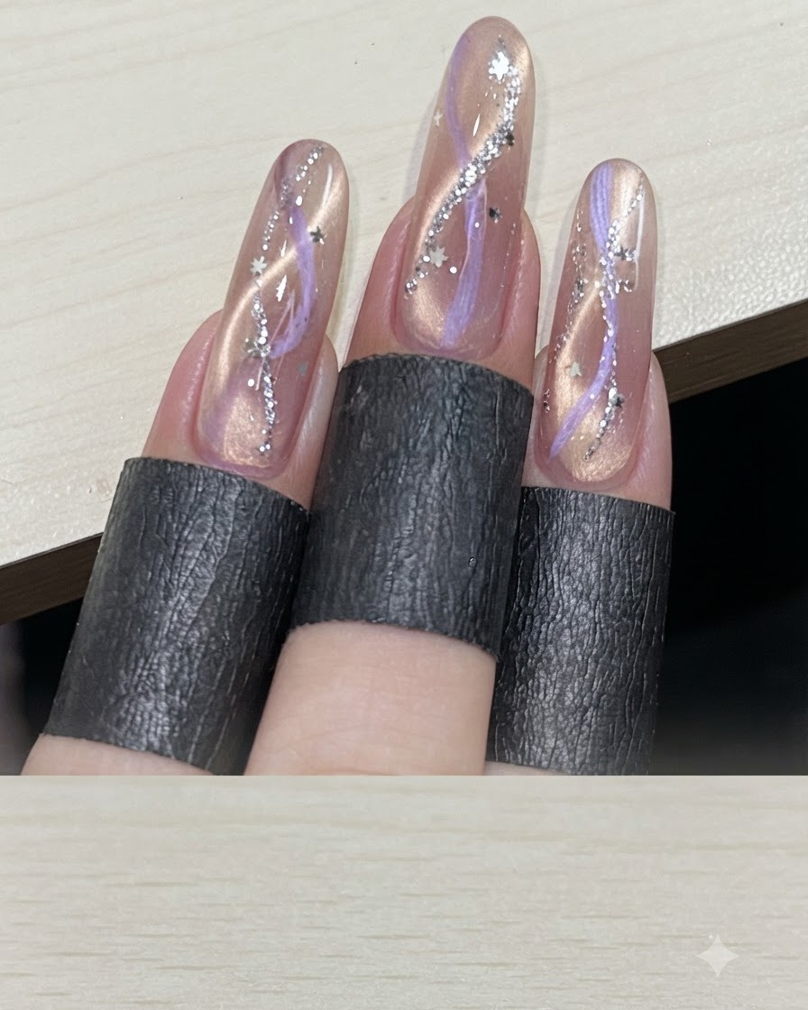 Une vue de plusieurs doigts affichant des manucures cat-eye à ruban finies et ornées de sequins détoiles argentés.