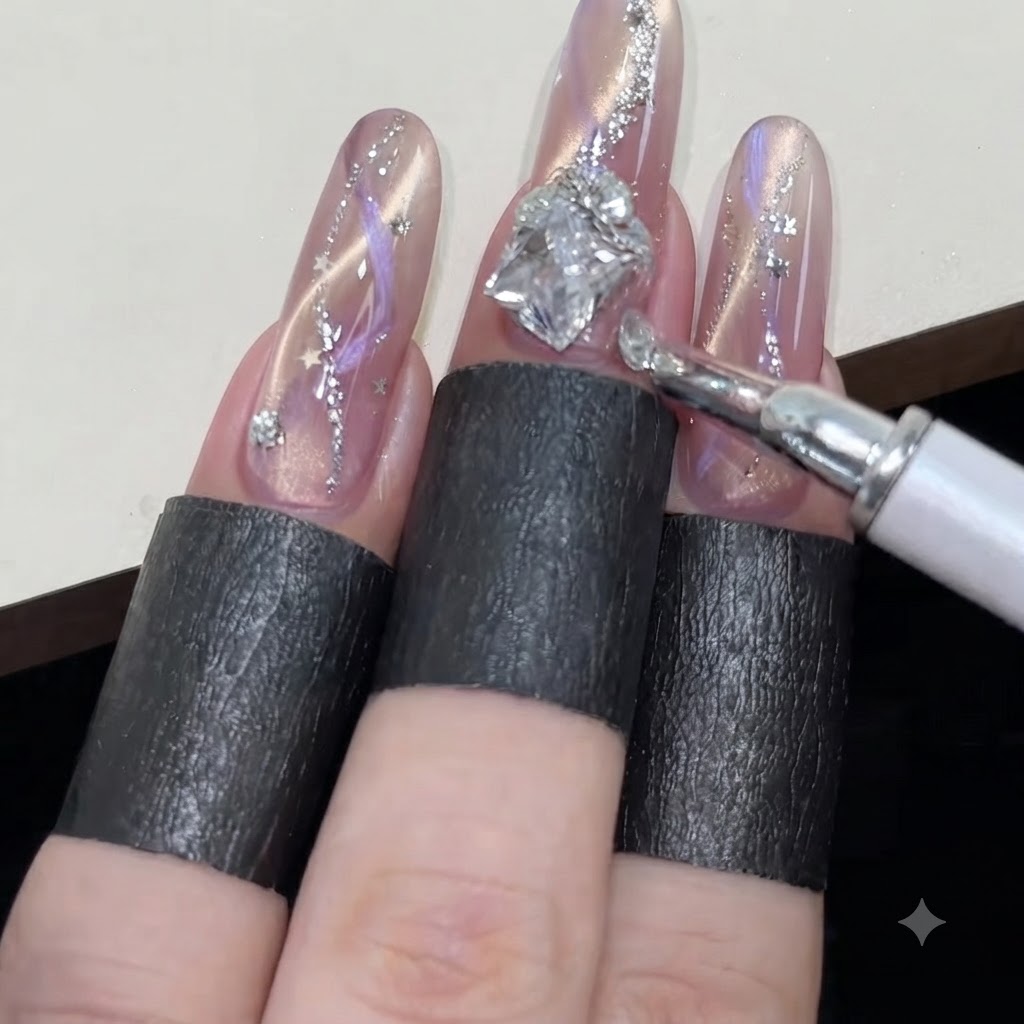 Un stylo à cire disposant de petits strass ronds autour dun grand bijou en diamant sur un ongle cat-eye rose scintillant.