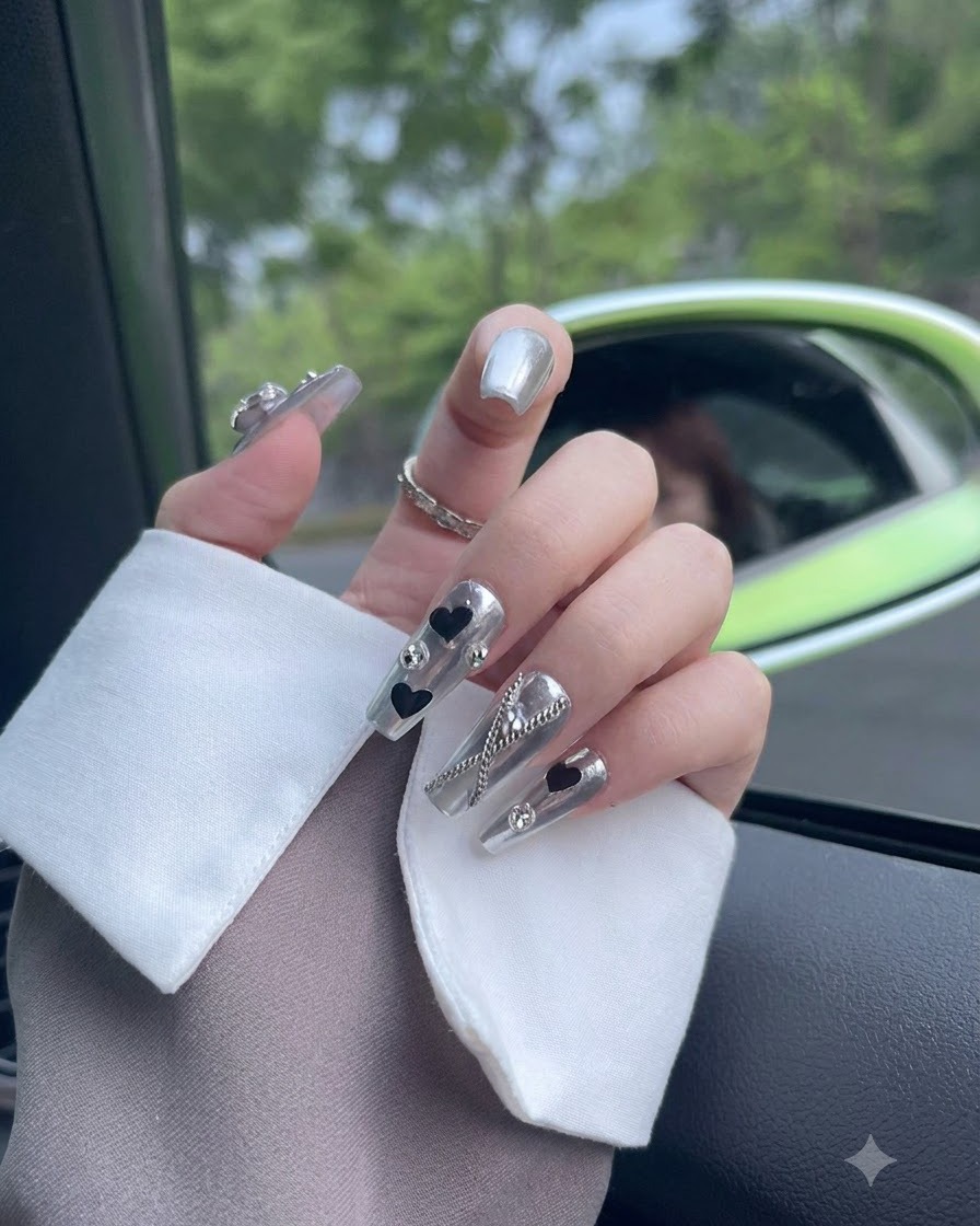 Gros plan centré sur un ongle de pouce orné dune finition chromée et dun élément en cristal étincelant.