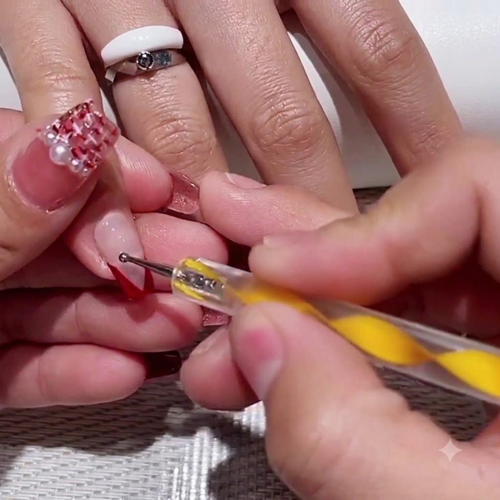 Un dotting tool à manche jaune plaçant deux petits points rouges dans lespace négatif transparent dun ongle V-tip.