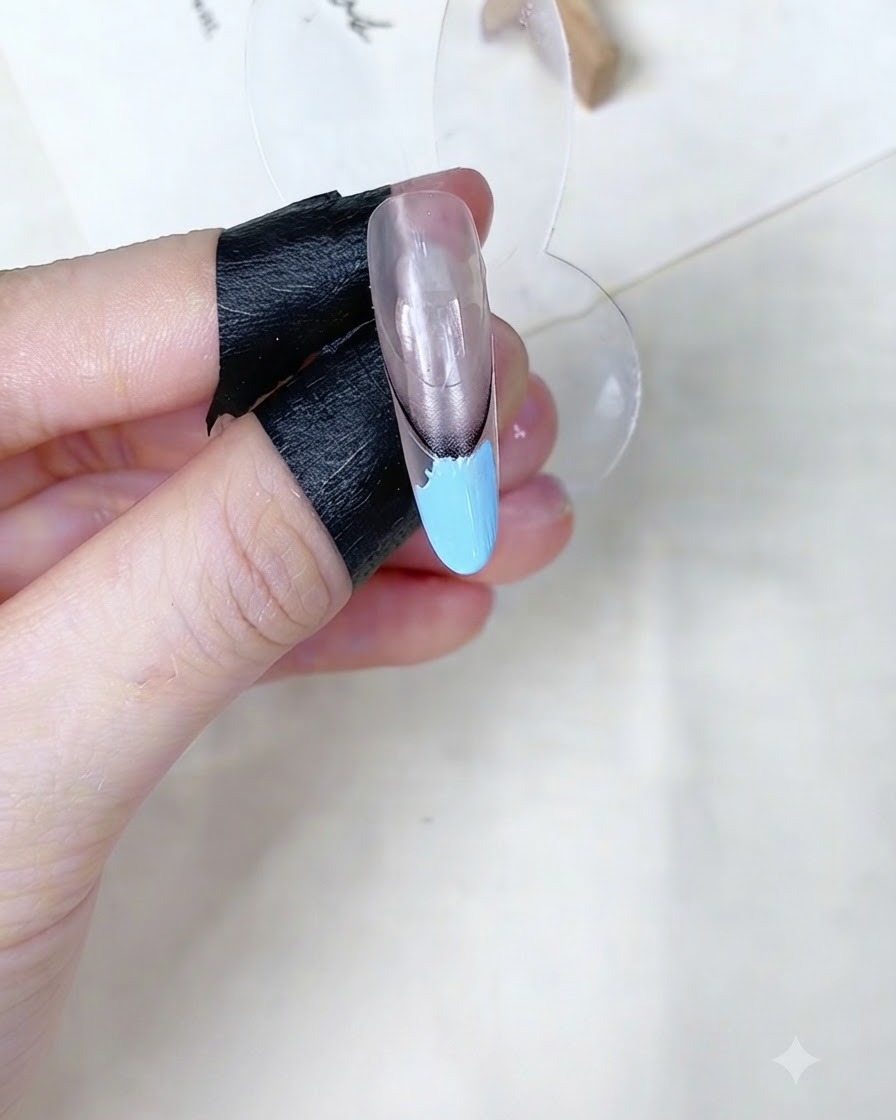 Une éponge à maquillage tamponnant la zone de gel bleu bébé sur un support dongle.