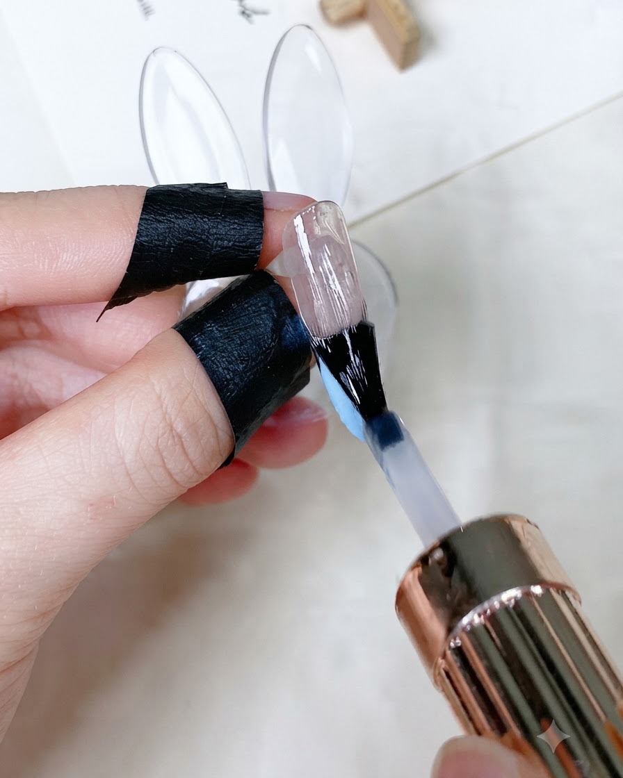 Un pinceau appliquant un top coat transparent brillant sur un onglet peint.