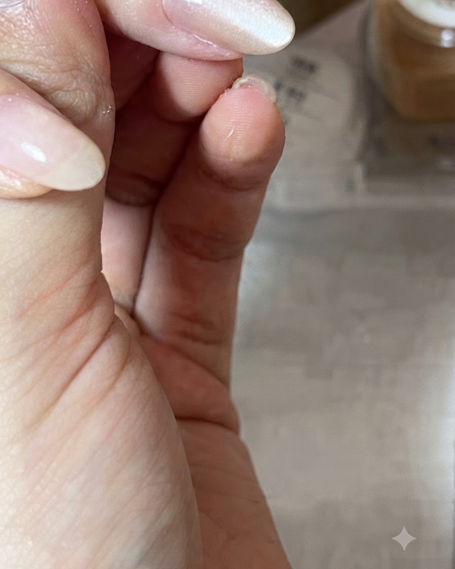 Gros plan dune main maintenant un aimant cylindrique en diagonale au-dessus dun ongle verni en nude brillant pour modeler le reflet lumineux cat-eye.