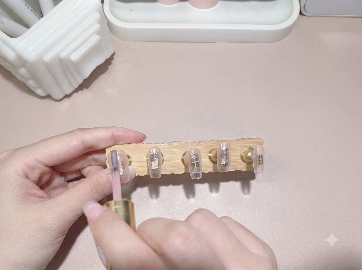 Un pinceau appliquant un vernis gel translucide couleur thé au lait sur une capsule dongle.