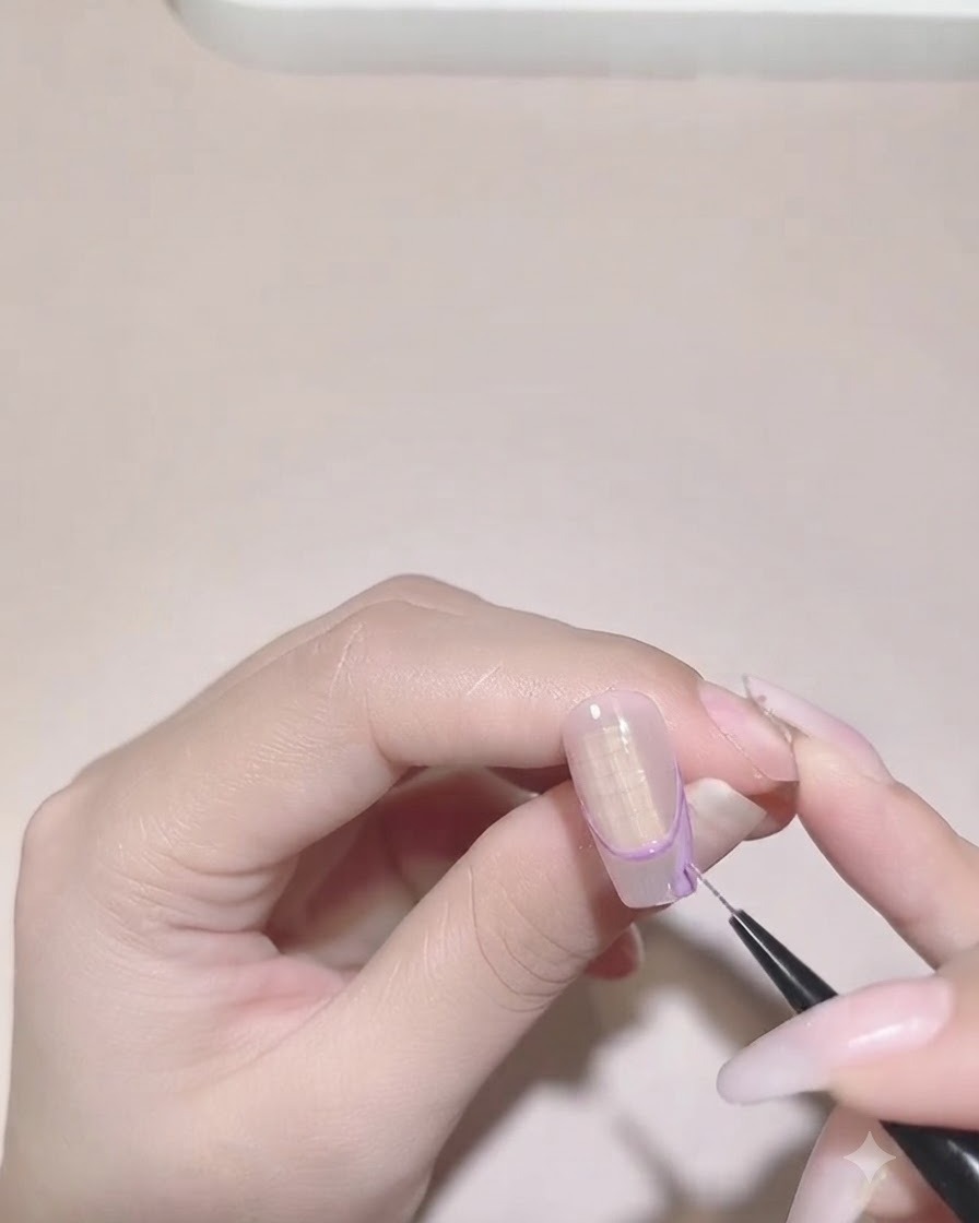 Un pinceau de détail remplissant la couleur violette à lintérieur de la limite de la French tip irrégulière sur un ongle.