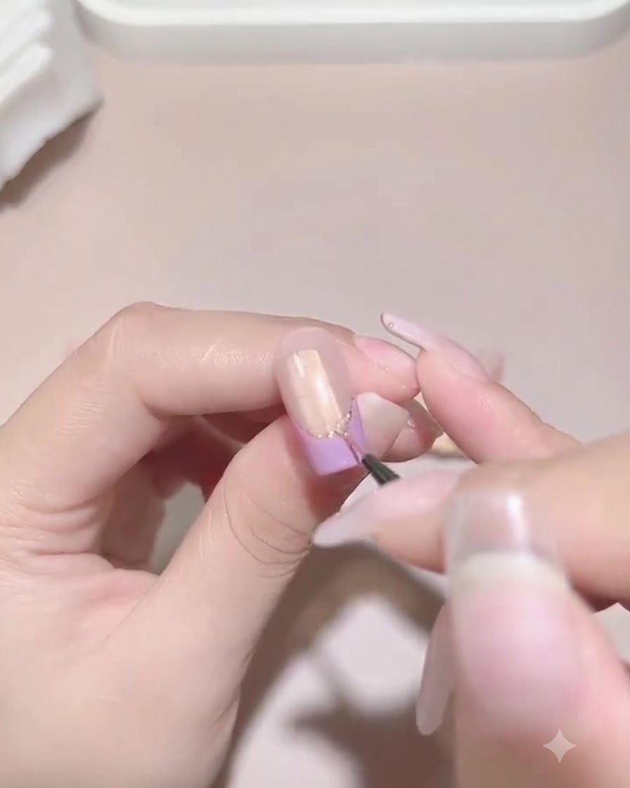 Un pinceau de détail fin appliquant minutieusement du gel de scellement autour de la base des perles et des strass fixés sur un ongle manucuré.