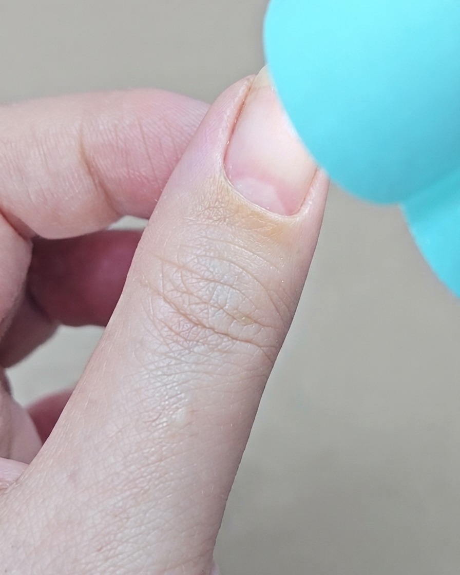 Une lampe UV bleue portative positionnée directement au-dessus dun doigt pour catalyser la couche de base en gel.