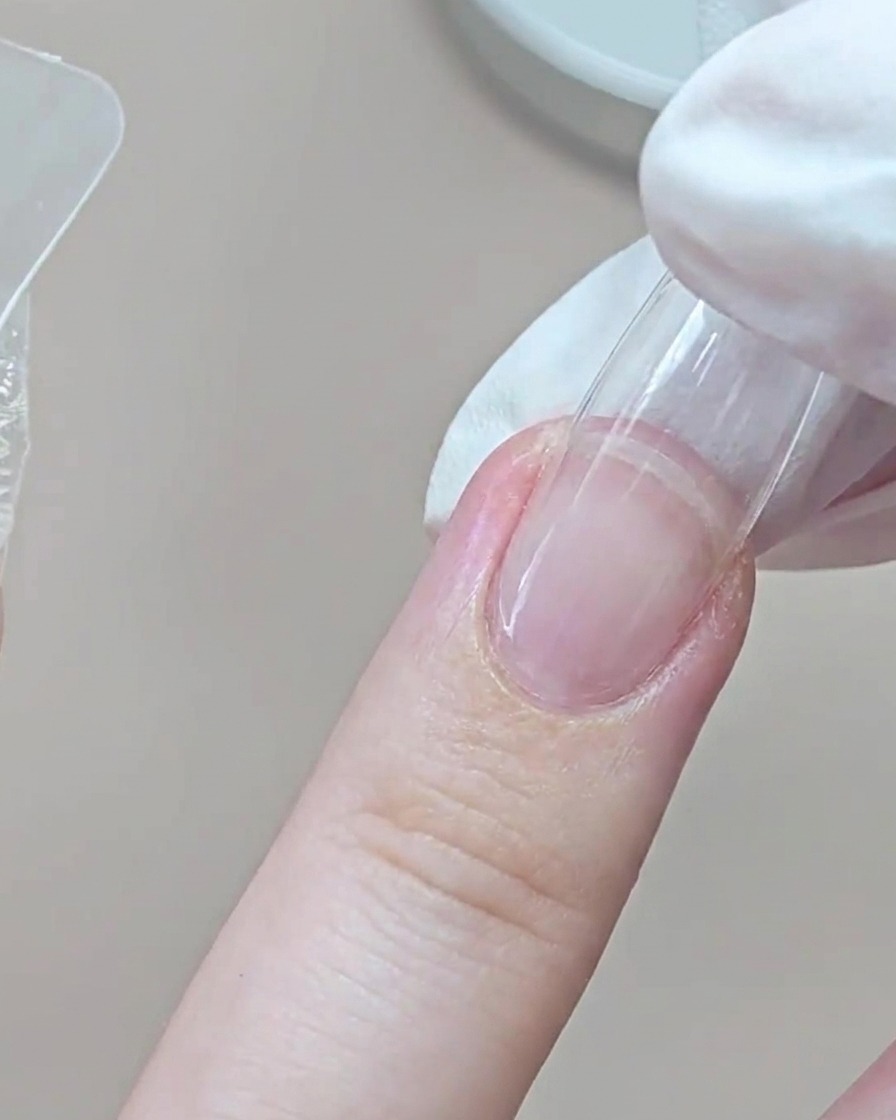 Un doigt ganté presse un dual form transparent sur lannulaire près de la zone des cuticules.