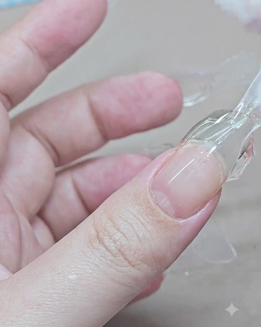 Une main pince et soulève un dual form en plastique transparent dune extension en gel durcie sur lindex.