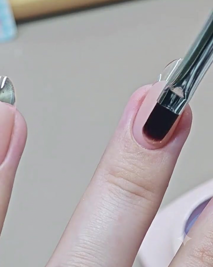 Un pinceau de nail art applique un top coat transparent brillant sur un ongle de manucure French terminé.